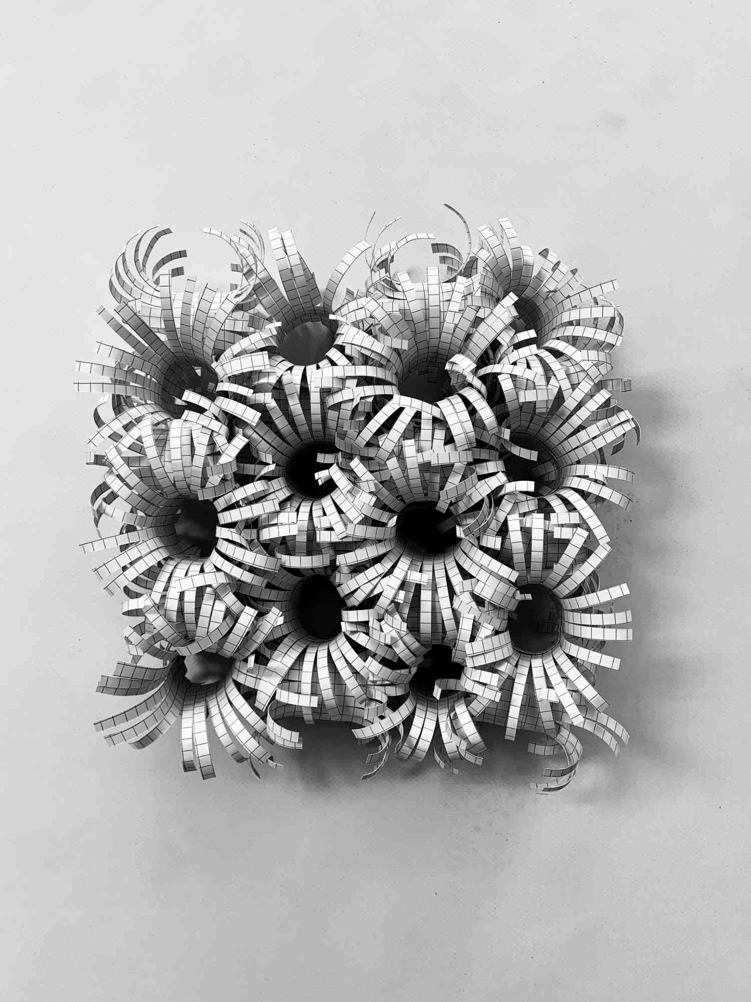 White folded-paper object with curled spokes, viewed from above